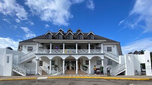 A two-story building with a balcony, a staircase, and a statue in front. - Ocho Rios Sandcastles King Suite with Balcony & Beach Access – Ideal for Couples (Ocho Rios)