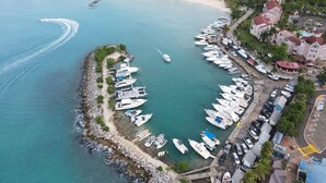 An aerial view of a marina with boats docked, a sandy beach, and surrounding residential buildings. - Ocho Rios Sandcastles King Suite with Balcony & Beach Access – Ideal for Couples (Ocho Rios)