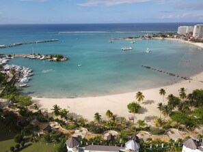 A coastal resort with a marina, sandy beach, and palm trees.