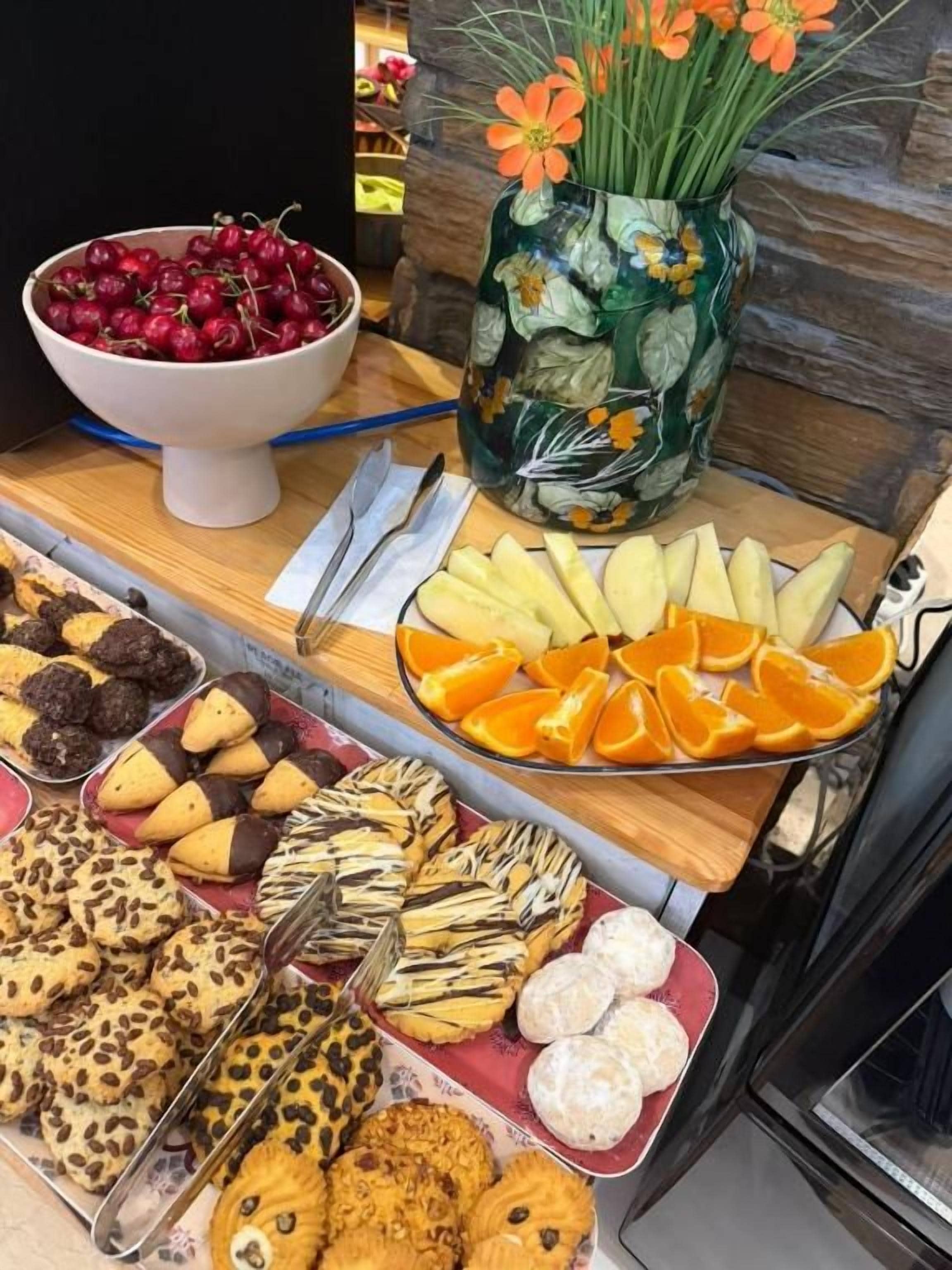 A buffet table with various food items including fruits, pastries, and cookies.