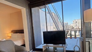 Una habitación de hotel moderna con un ventanal grande, un televisor de pantalla plana, un sofá y una mesa de centro.