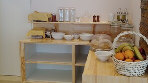 Una mesa buffet de madera con varios recipientes, frascos y una cesta de fruta.