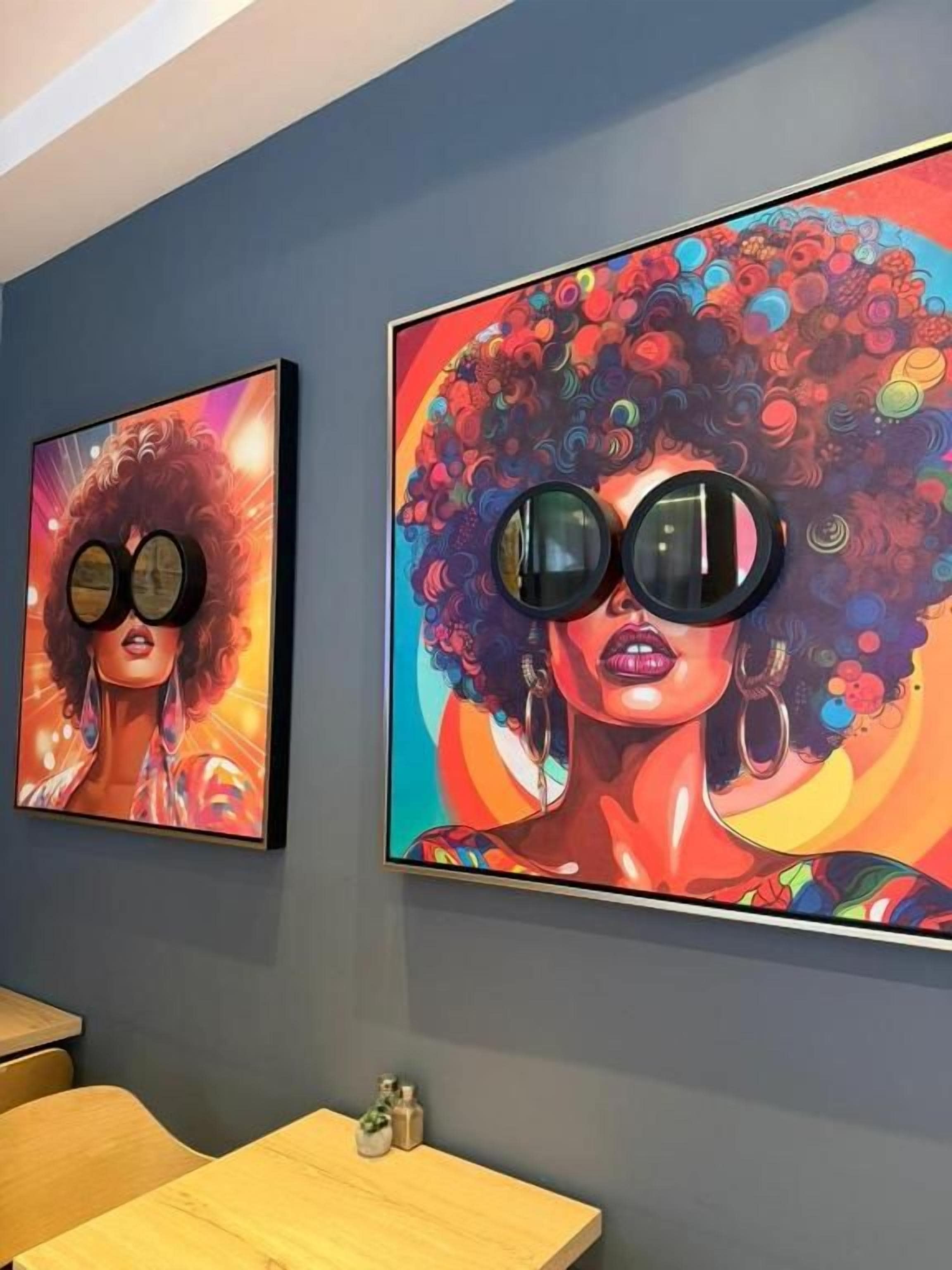 Deux œuvres d’art encadrées sont accrochées au mur, une salle à manger avec une table et des chaises en bois, et un petit objet décoratif est posé sur la table.