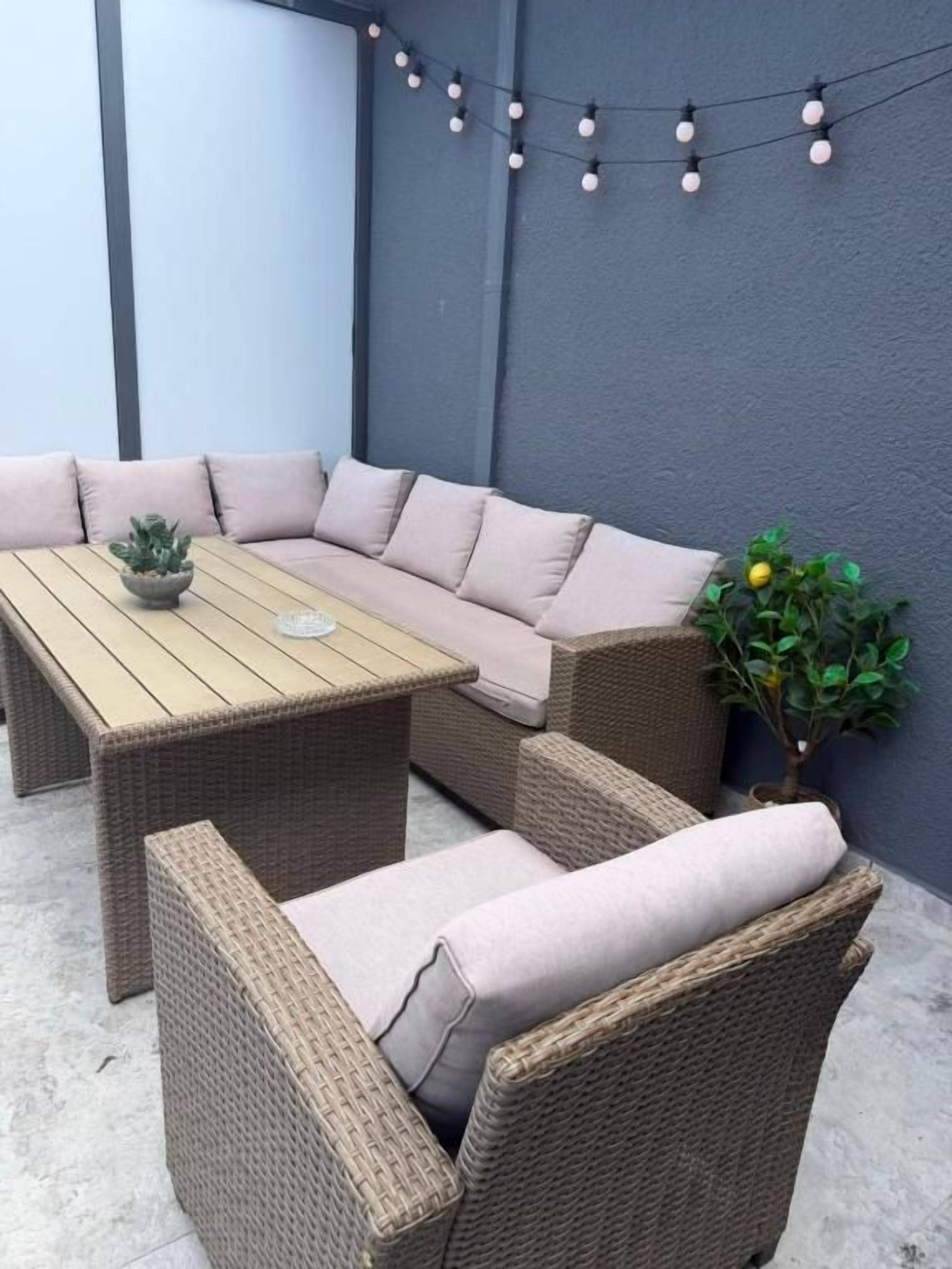 Eine Sitzecke mit einer Couch und Sesseln, einem Holztisch und einem Blumentopf.