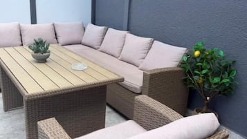 Eine Sitzecke mit einer Couch und Sesseln, einem Holztisch und einem Blumentopf.