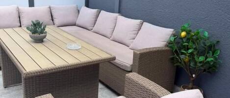 Eine Sitzecke mit einer Couch und Sesseln, einem Holztisch und einem Blumentopf.