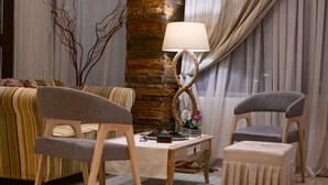 Un salón acogedor con un sofá, dos sillones, una mesita de centro y una lámpara.