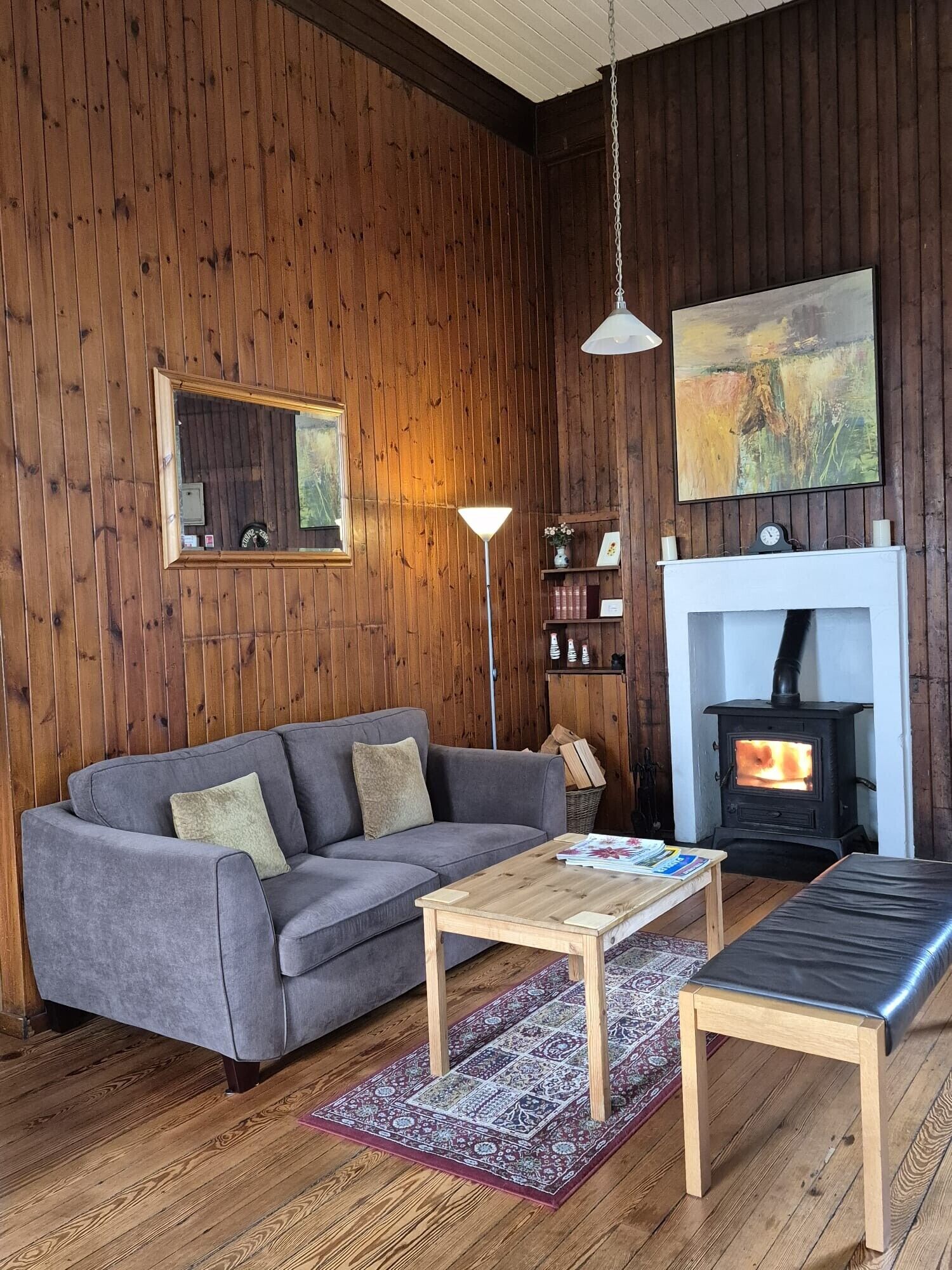 Una sala de estar acogedora con sofá, mesa de centro, chimenea y paredes de madera.