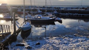 A marina with boats docked, a pier, and a calm water body. - Helmsdale Lodge (Helmsdale)
