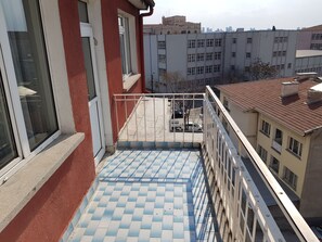 Ein Balkon mit Schachbrettboden, einem Metallgeländer und Blick auf umliegende Gebäude.