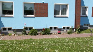 A building with multiple windows, some with shutters, and a brick section on the facade. - Haus Marinus (Fehmarn)