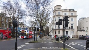 A street intersection with traffic lights, a bus, and a building with classical architecture.