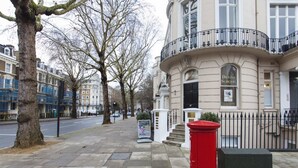 A building with a dental surgery sign, a red post box, and a sidewalk with trees.