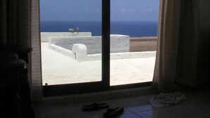 Une pièce dotée d’une grande porte-fenêtre coulissante donnant sur une terrasse avec vue sur la mer.