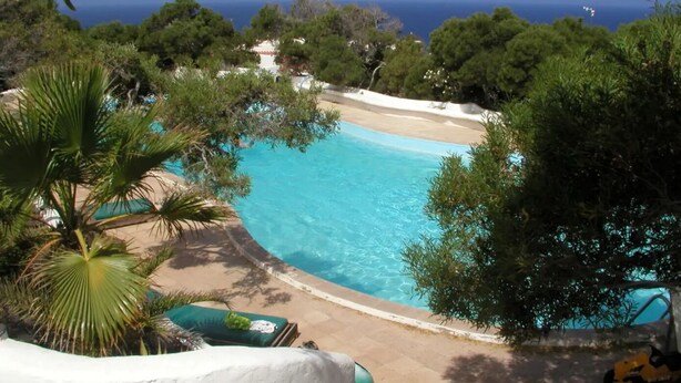 Une piscine entourée d’arbres et une plage.