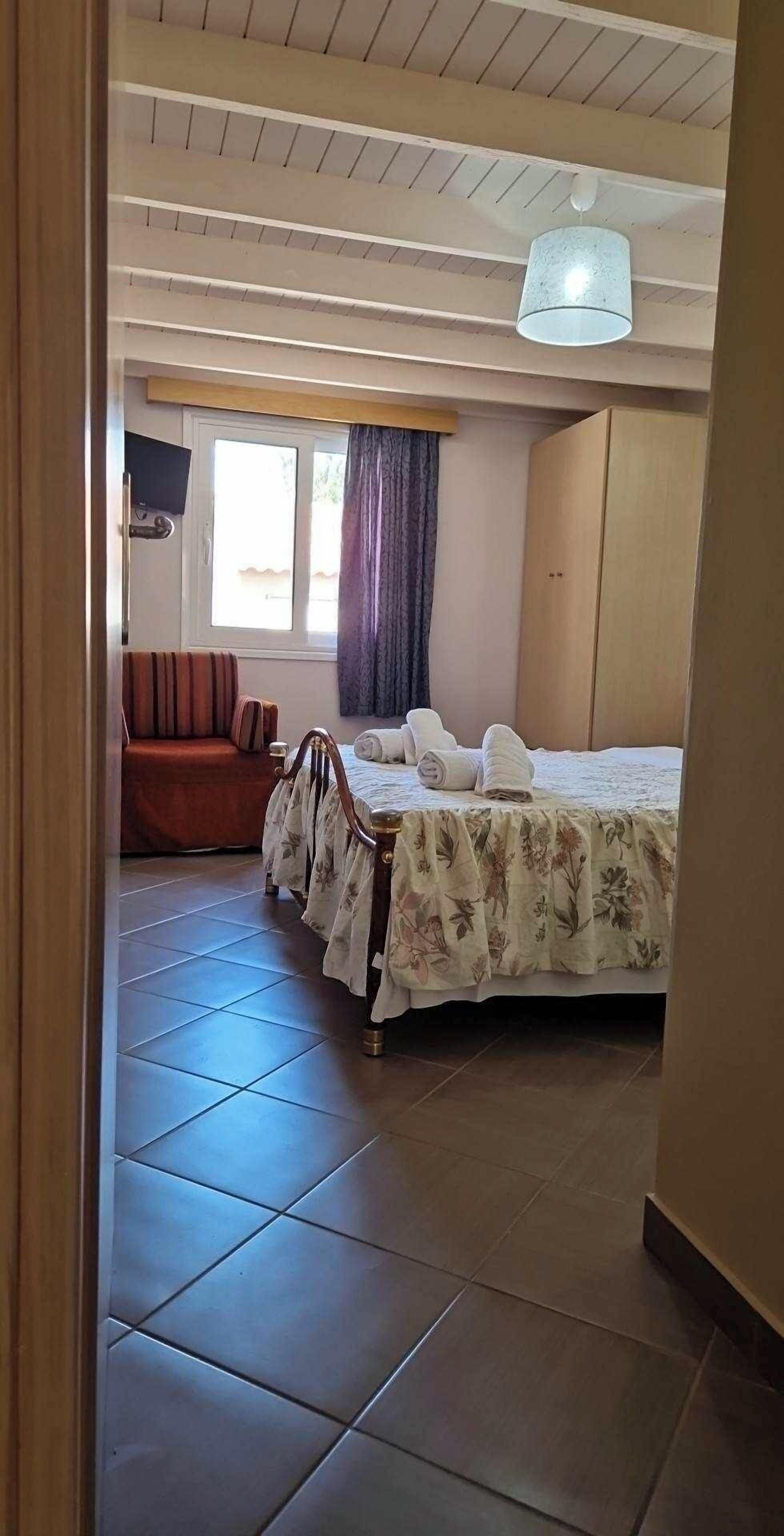 Ein Hotelzimmer mit Bett, Sessel, Kleiderschrank und Fernseher.