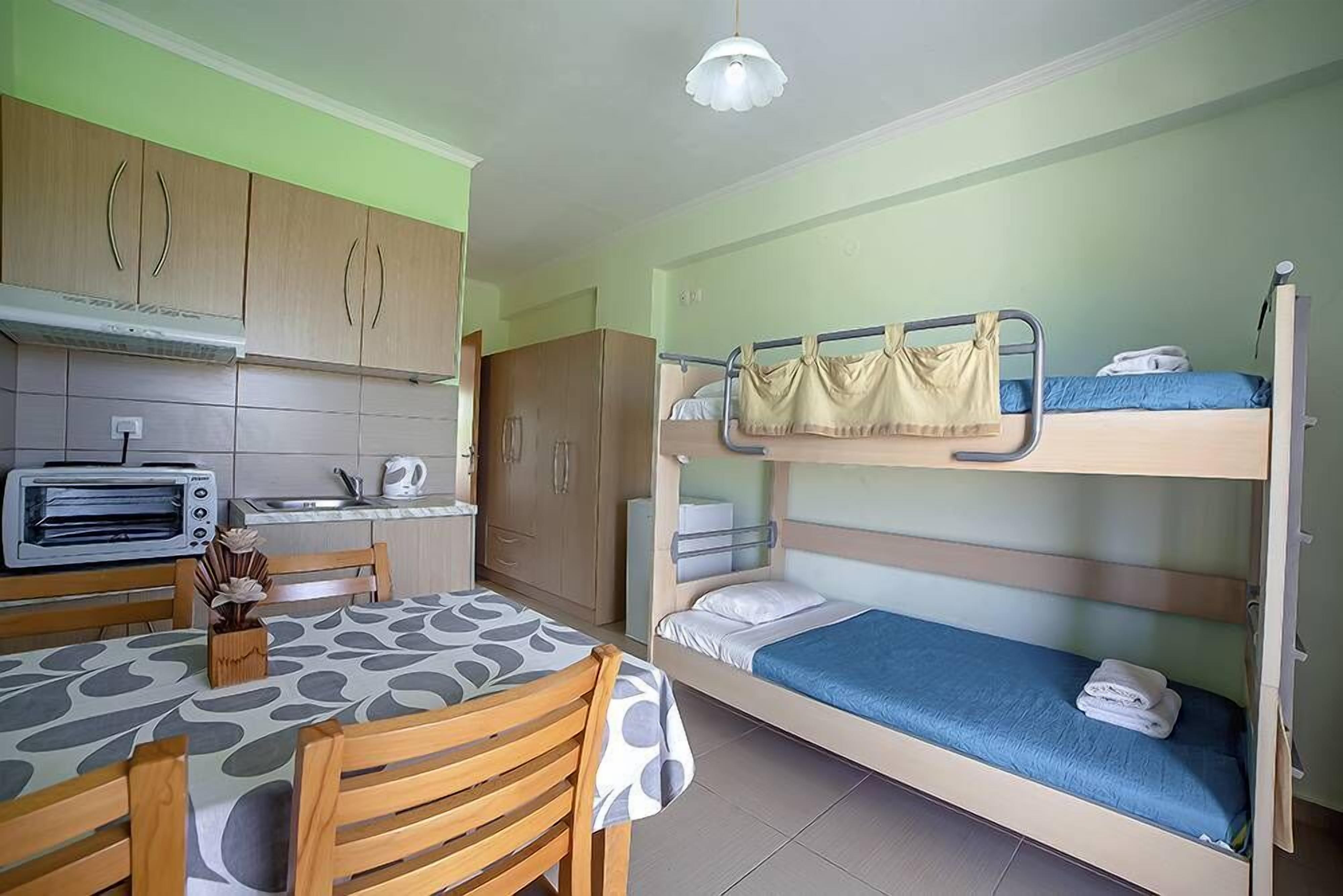 A compact room with bunk beds, a kitchenette, and a dining area.