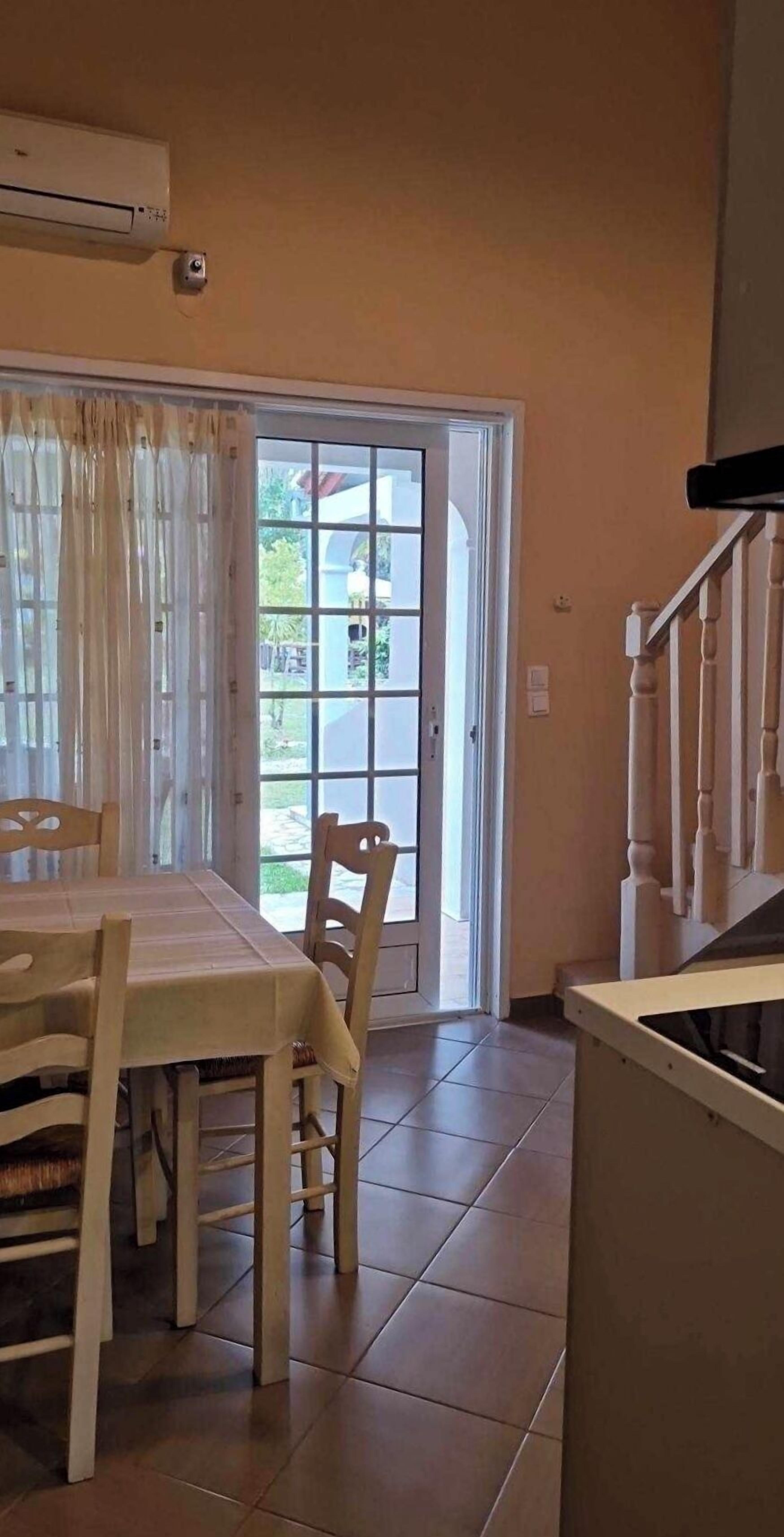 Ein Essbereich mit Tisch und Stühlen, eine Schiebetür zum Außenbereich und eine Treppe.