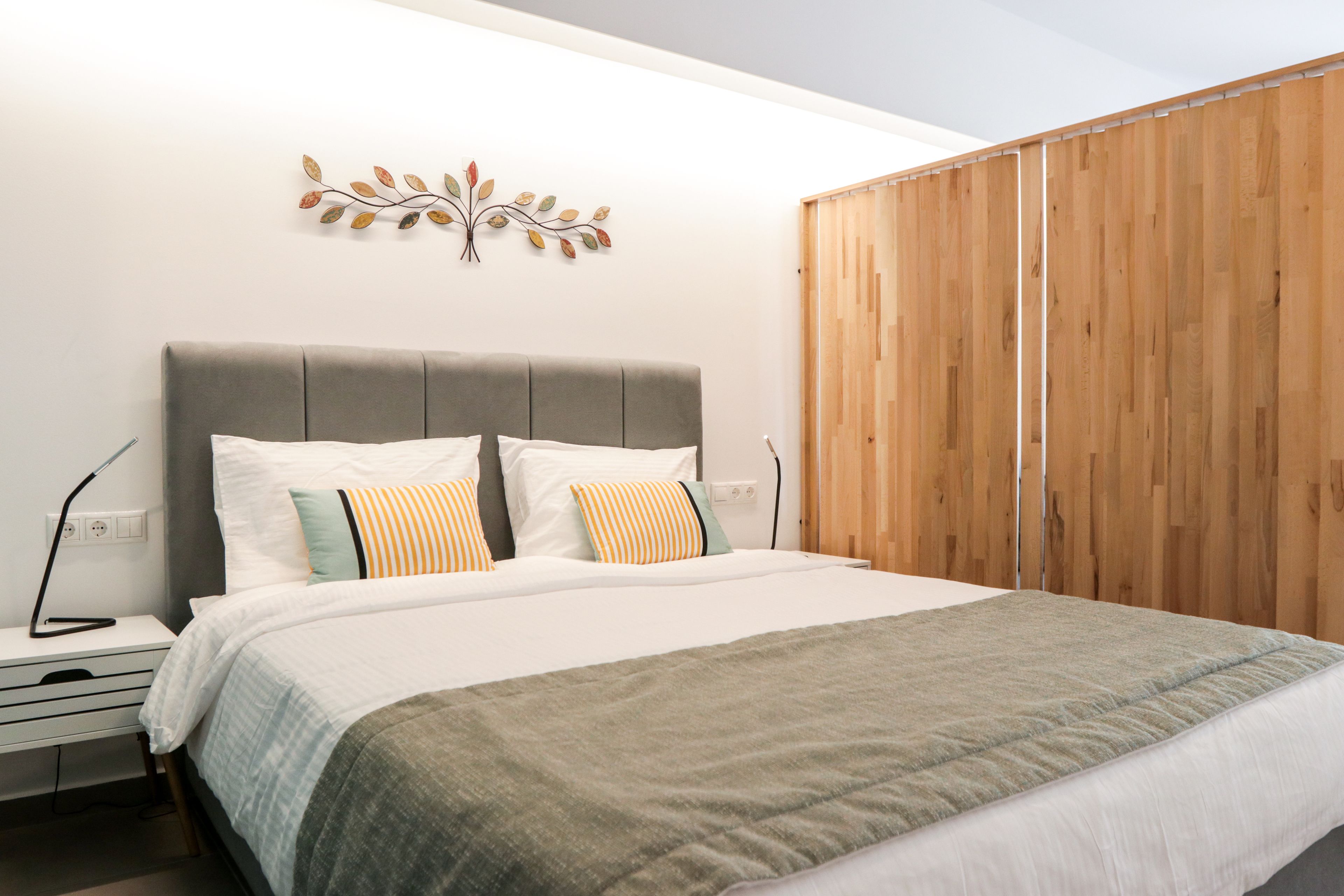 Un dormitorio con cama, mesitas de noche, un adorno en la pared y un armario de madera.