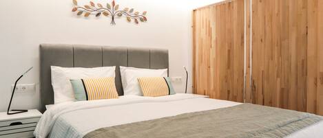 Un dormitorio con cama, mesitas de noche, un adorno en la pared y un armario de madera.