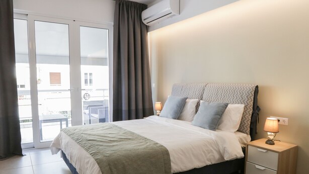 Una habitación de hotel con cama, mesitas de noche y vistas a un espacio exterior por una puerta corrediza.
