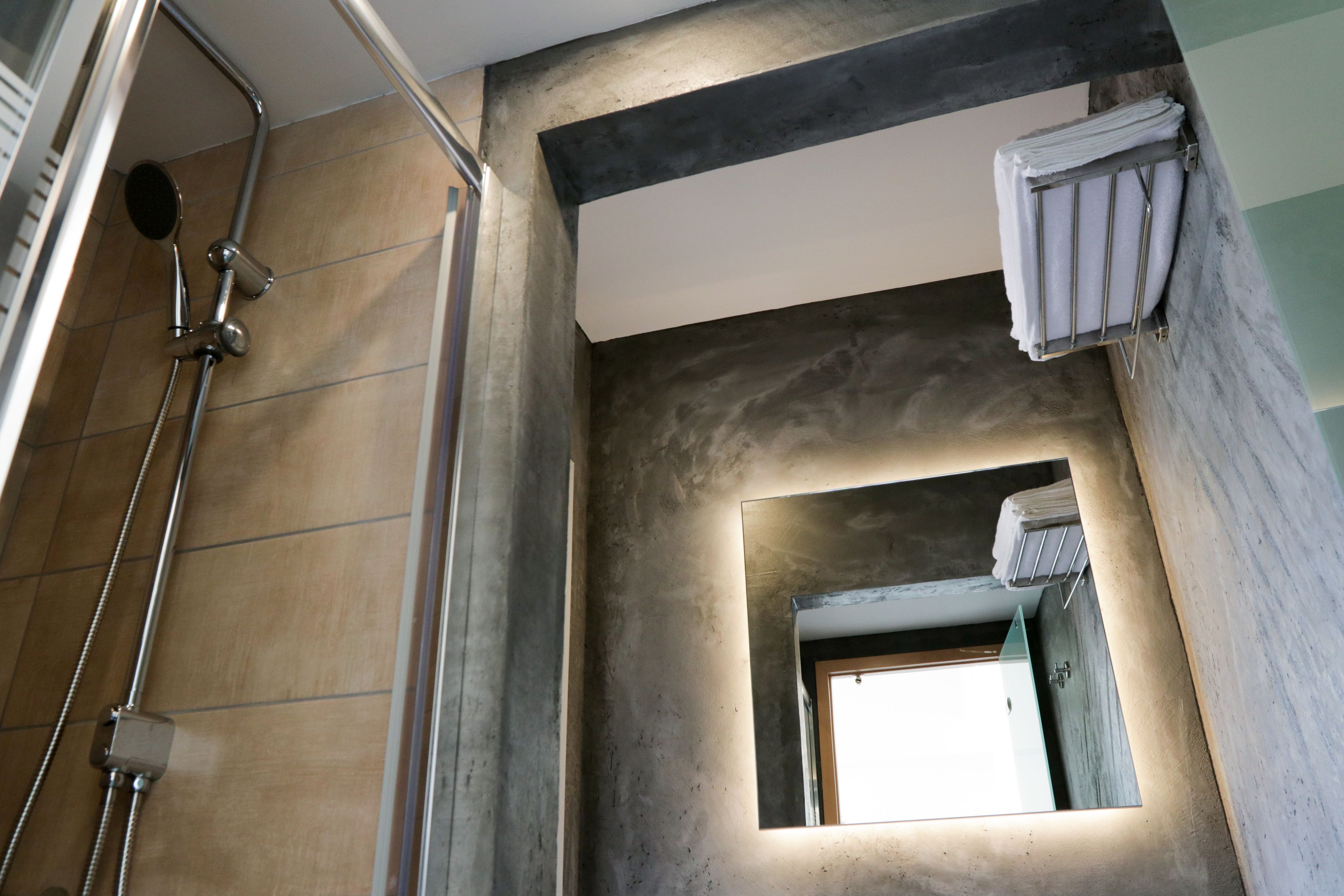 A bathroom with a shower, a towel rack, and a mirror.
