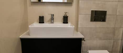 A bathroom with a white sink, black cabinet, and a toilet.