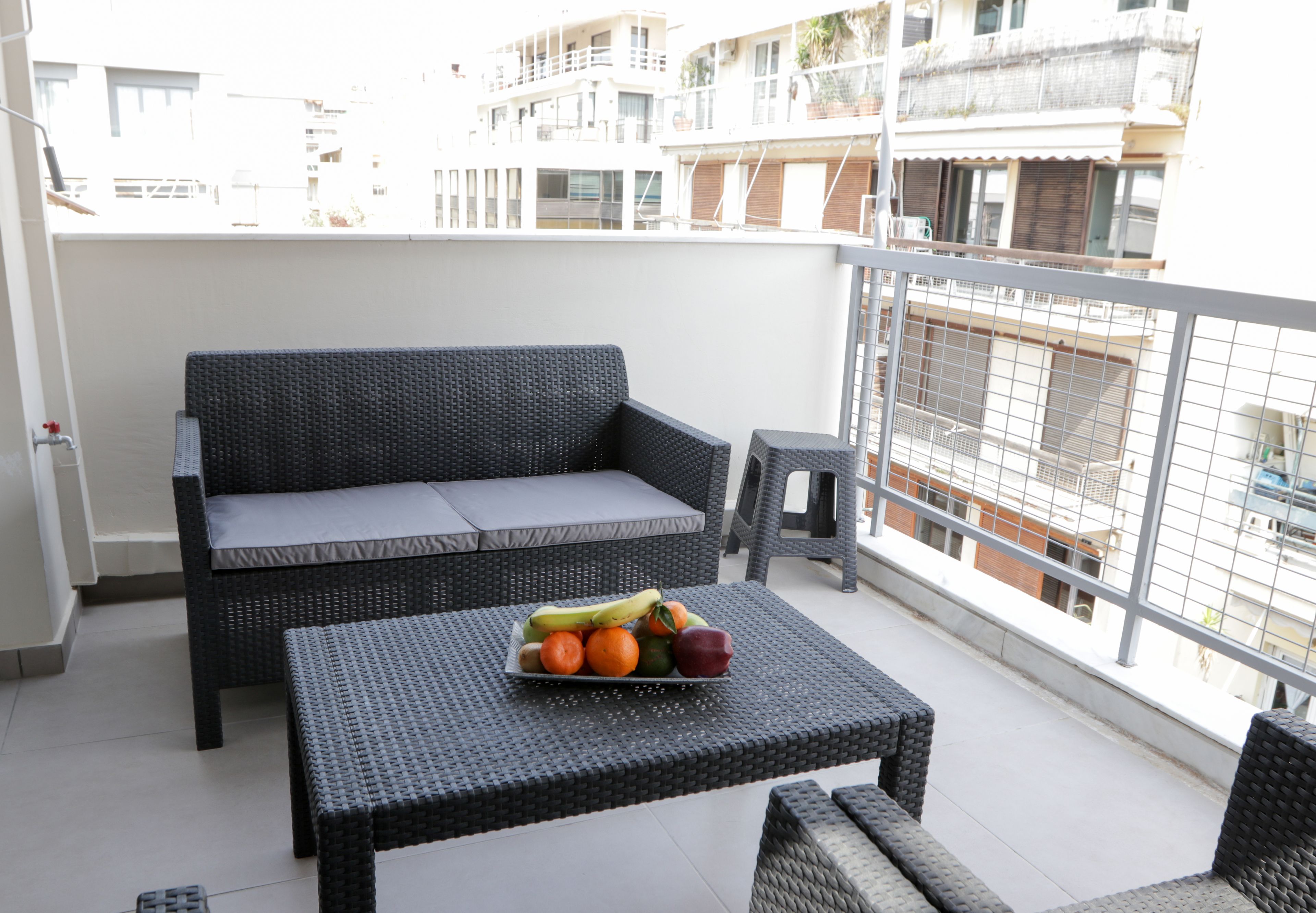 Un balcone con un divano in vimini e un tavolino con della frutta.