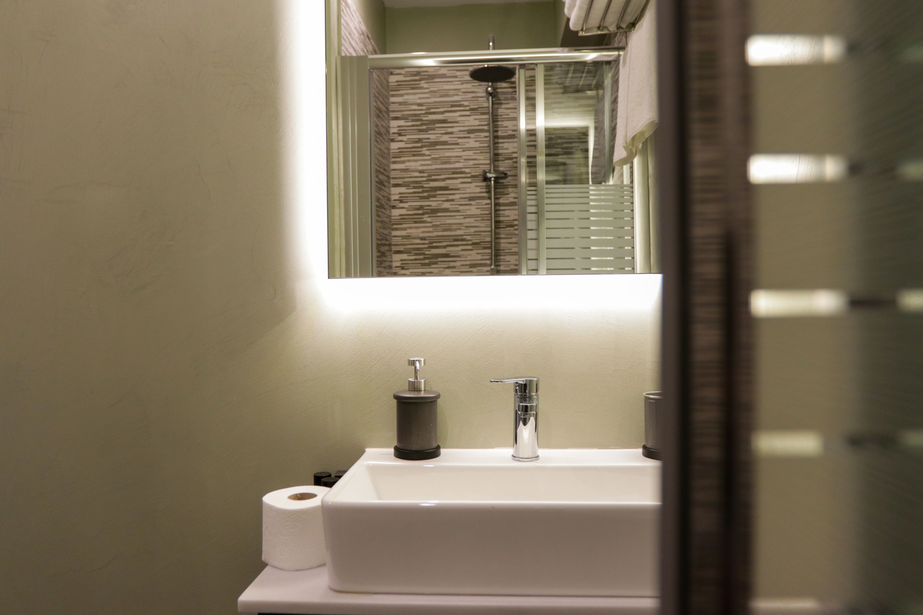 A bathroom with a white sink, a mirror, and a shower.