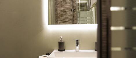 A bathroom with a white sink, a mirror, and a shower.