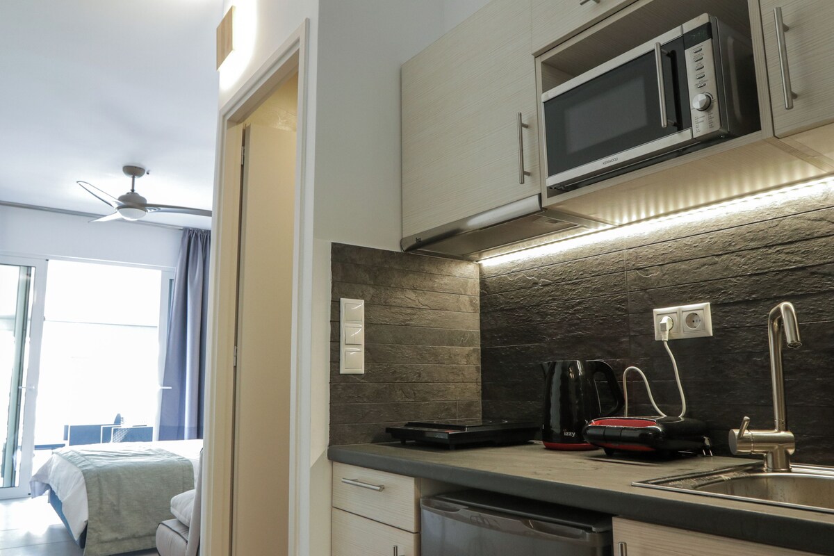 A compact kitchen with a microwave, kettle, and coffee maker.