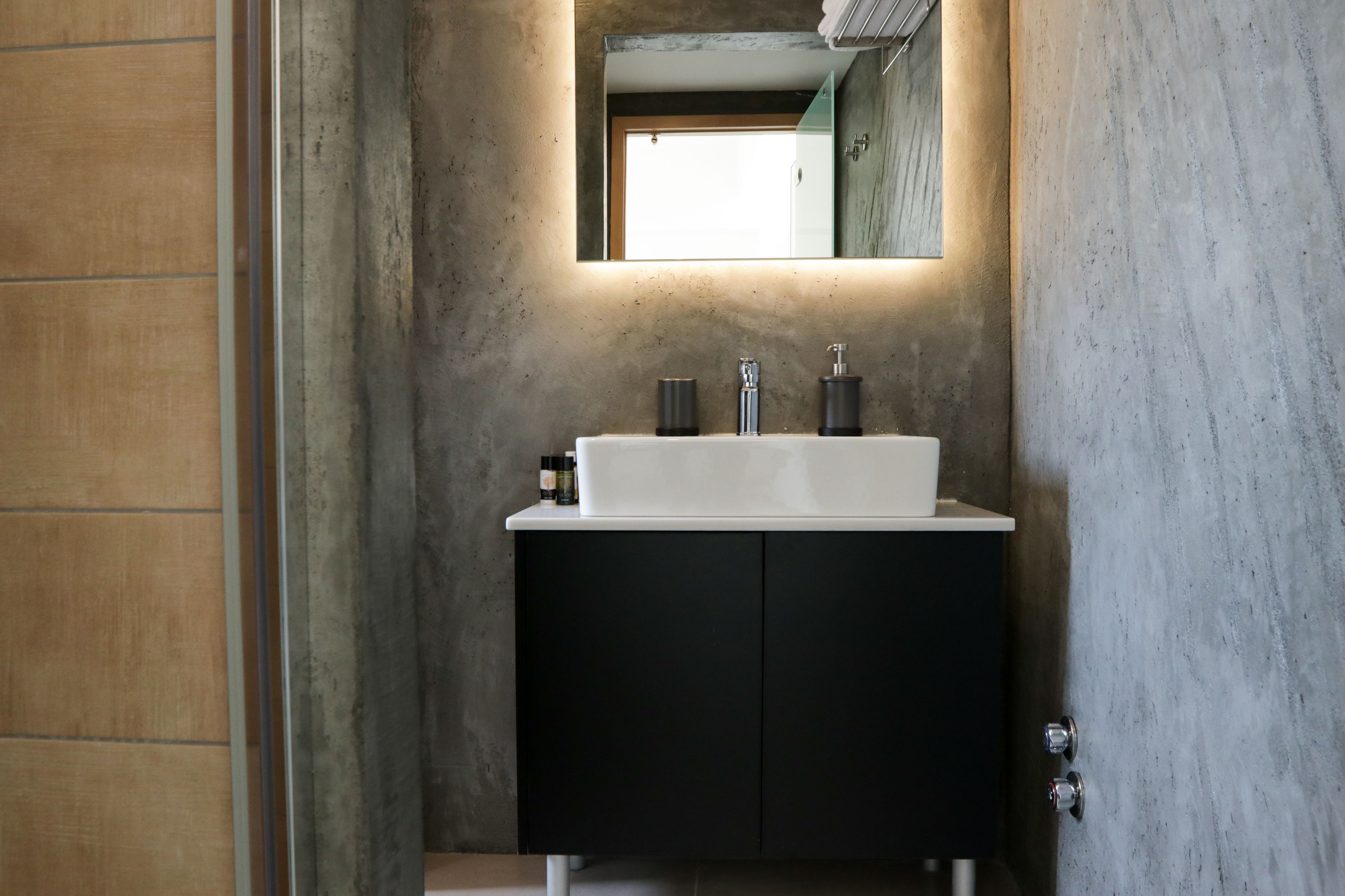 Un baño con lavamanos blanco, muebles negros y un espejo encima.