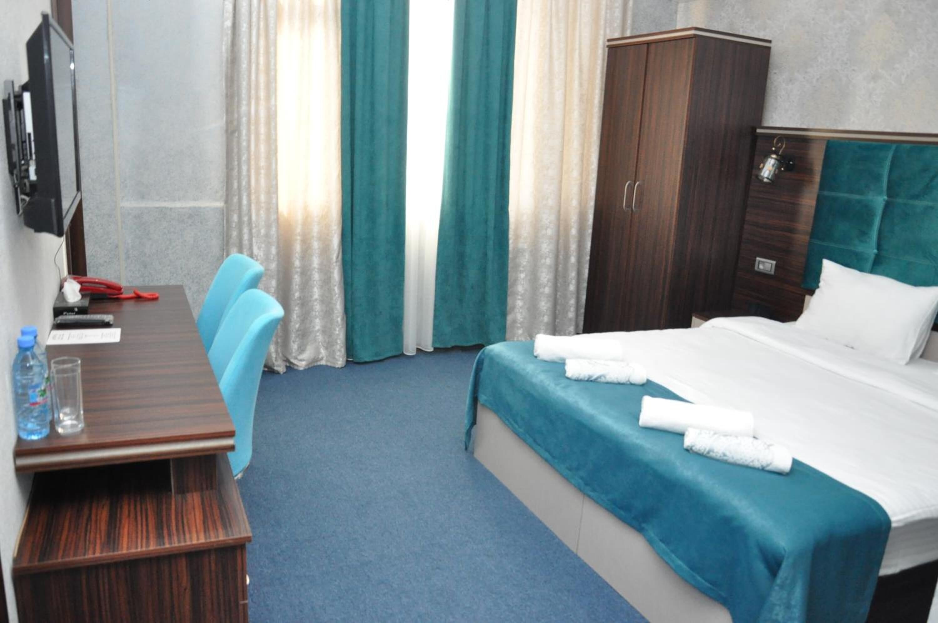 Een hotelkamer met een bed, een bureau, een stoel, een kledingkast en een televisie.
