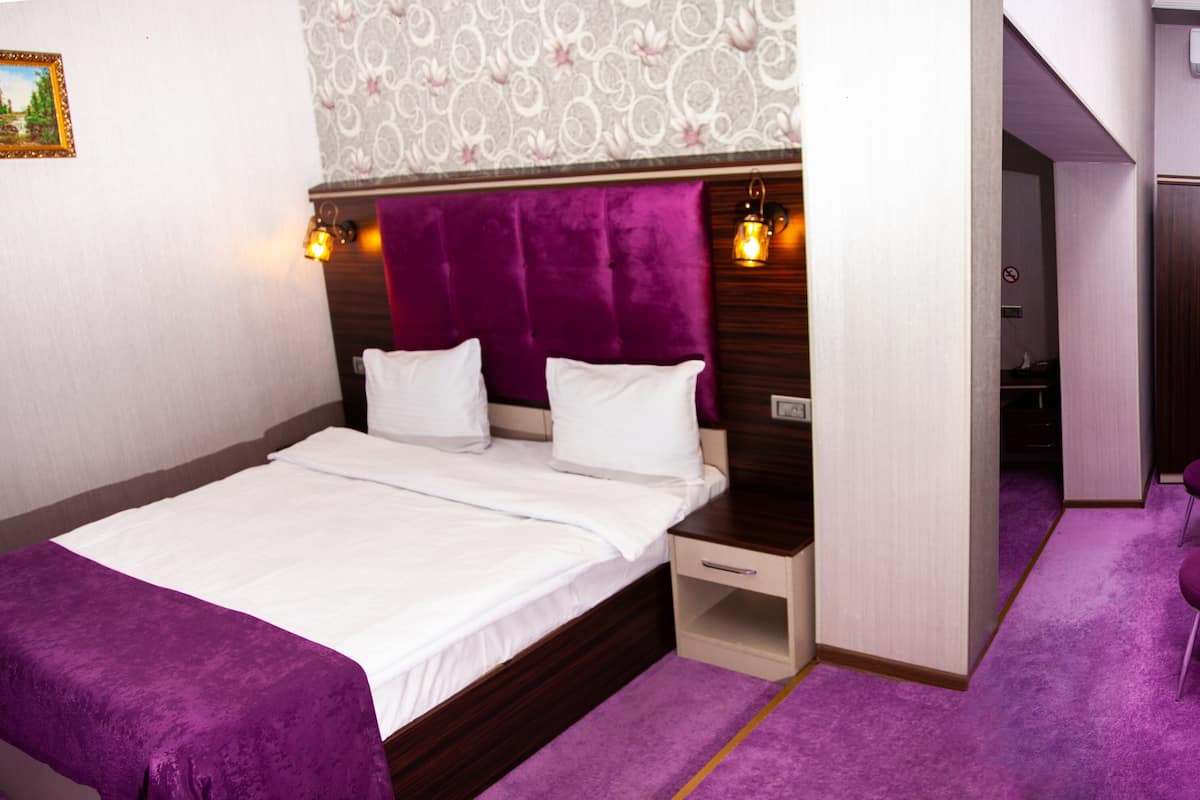 A bedroom with a bed, bedside table, and a chair.