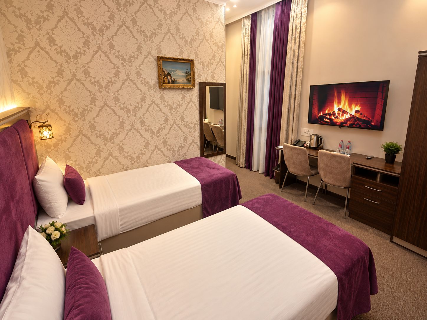 Una habitación de hotel con dos camas, un escritorio, una silla, un televisor y una chimenea.
