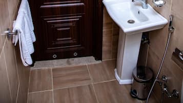 A bathroom with a wooden door, a white sink, a mirror, and a hairdryer.