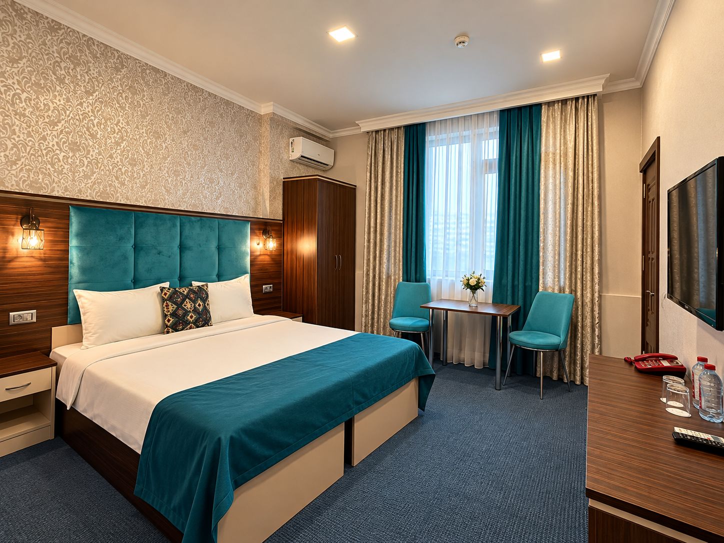 A hotel room with a large bed, a desk with a chair, a TV, and a window with curtains.