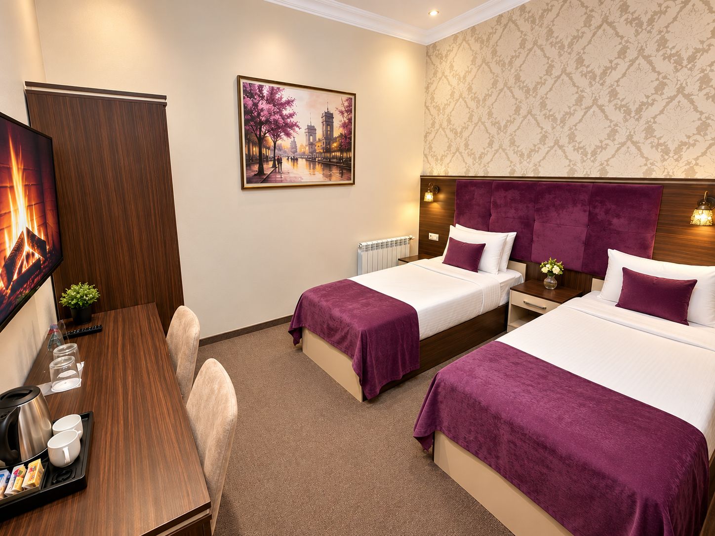A hotel room with two beds, a desk with a coffee maker, a TV, and a painting on the wall.