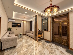 A modern living room with a fireplace, a sofa, a TV, and a decorative mirror. - Mildom Hotel Baku (Baku)