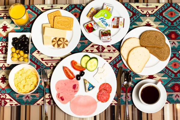 A table with breakfast items including bread, cheese, ham, eggs, and fruits.