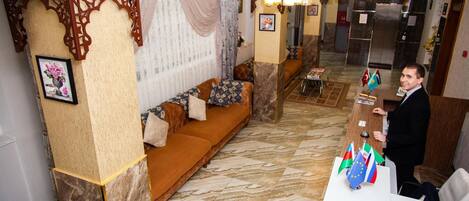 A lobby with a sofa, a reception desk, and a chandelier.