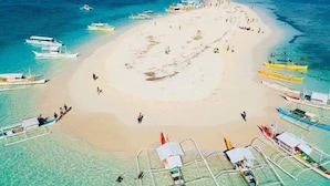 A beach with clear turquoise waters, a sandy center, and several boats anchored around. - Siargao Tropic Hostel (General Luna)