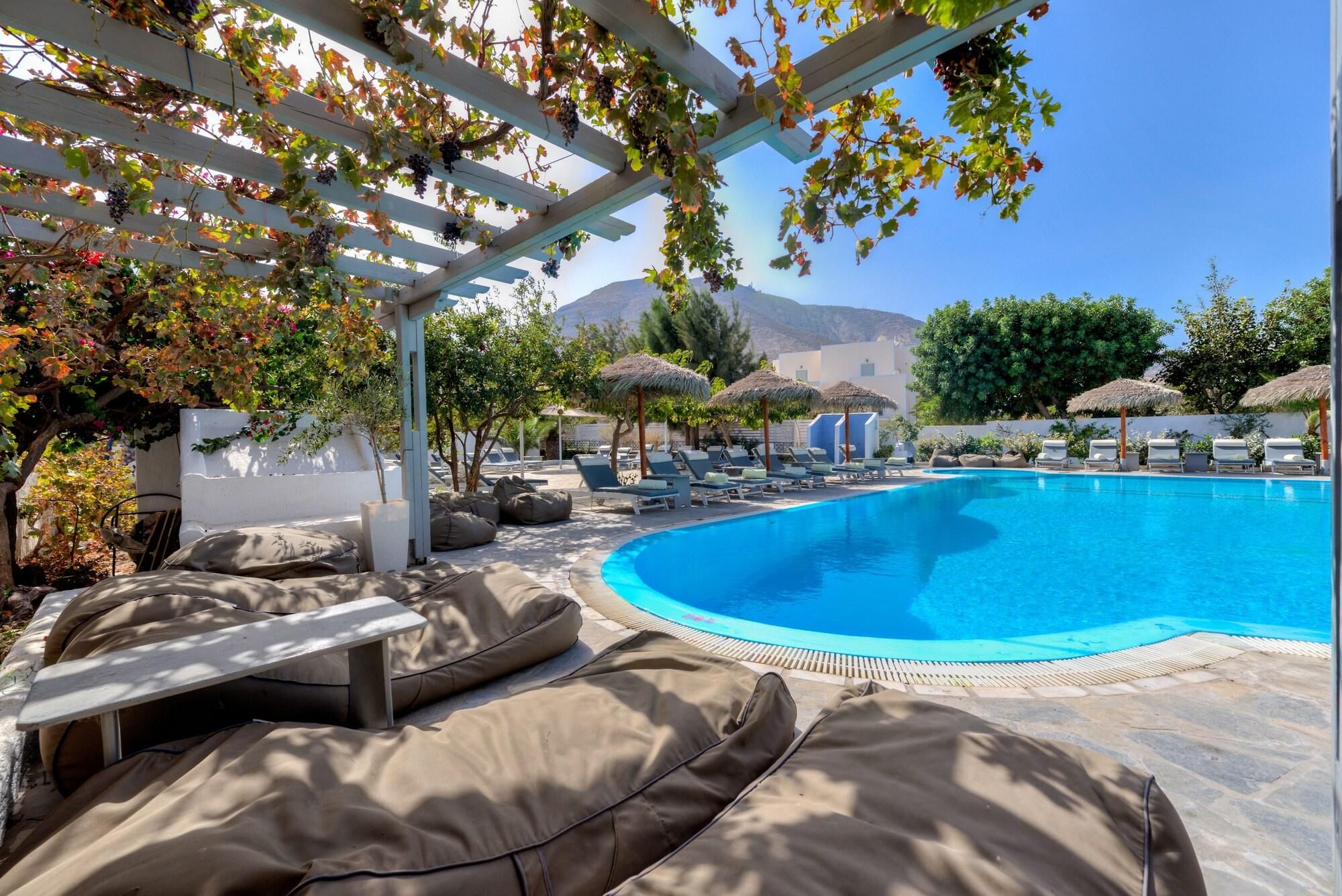 A pool area with lounge chairs and a pergola with vines.
