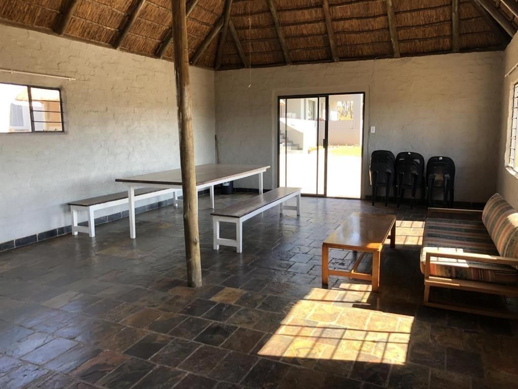 A spacious room with a thatched roof, a bench, a sofa, and a table.