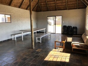A spacious room with a thatched roof, a bench, a sofa, and a table.