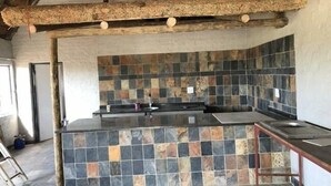 A kitchen with a stone backsplash and a wooden ceiling. - Spendpenny Guest Farm (Kgetlengrivier)
