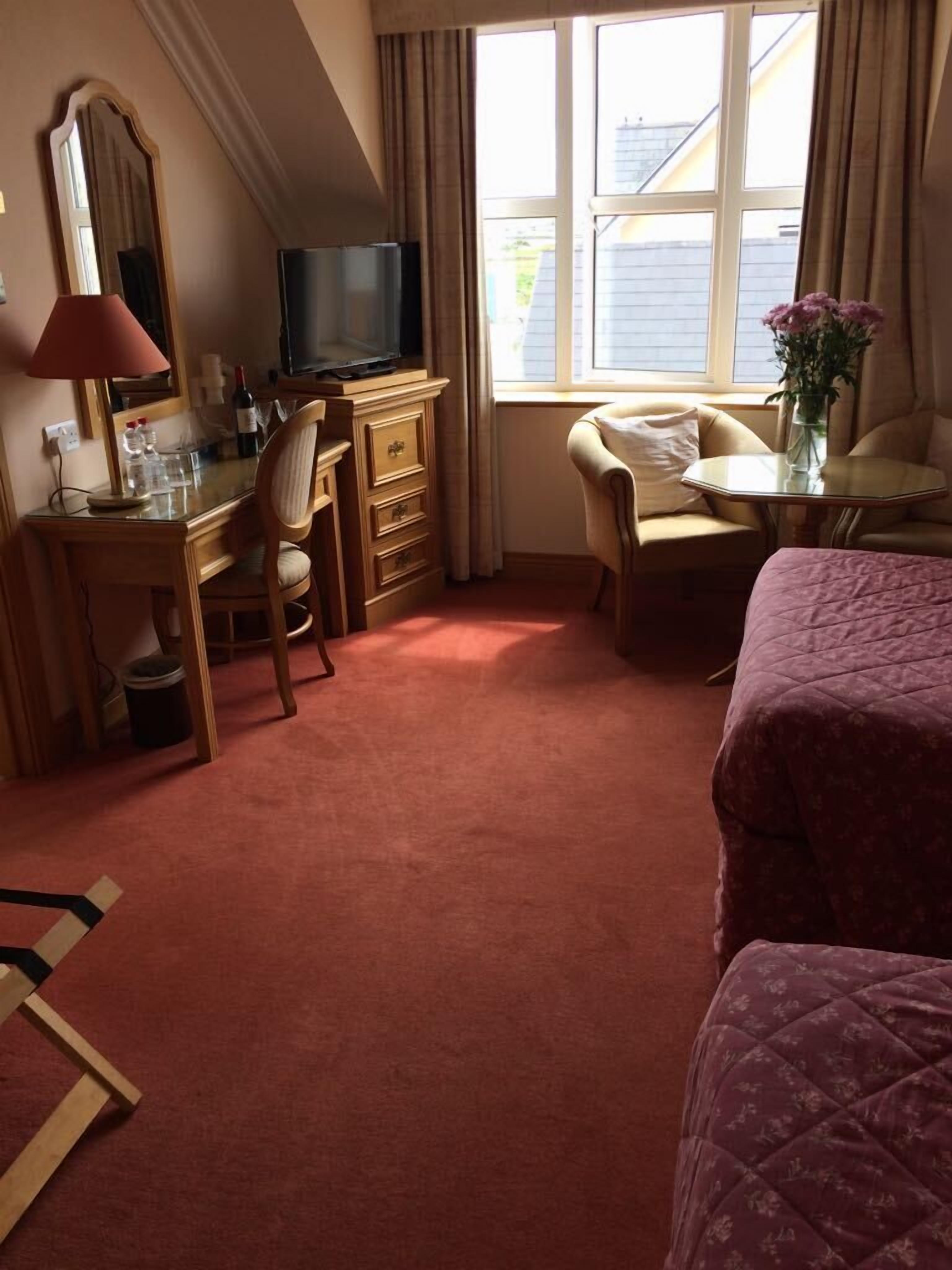 Ein Hotelzimmer mit Schreibtisch, Stuhl, Fernseher und Bett.