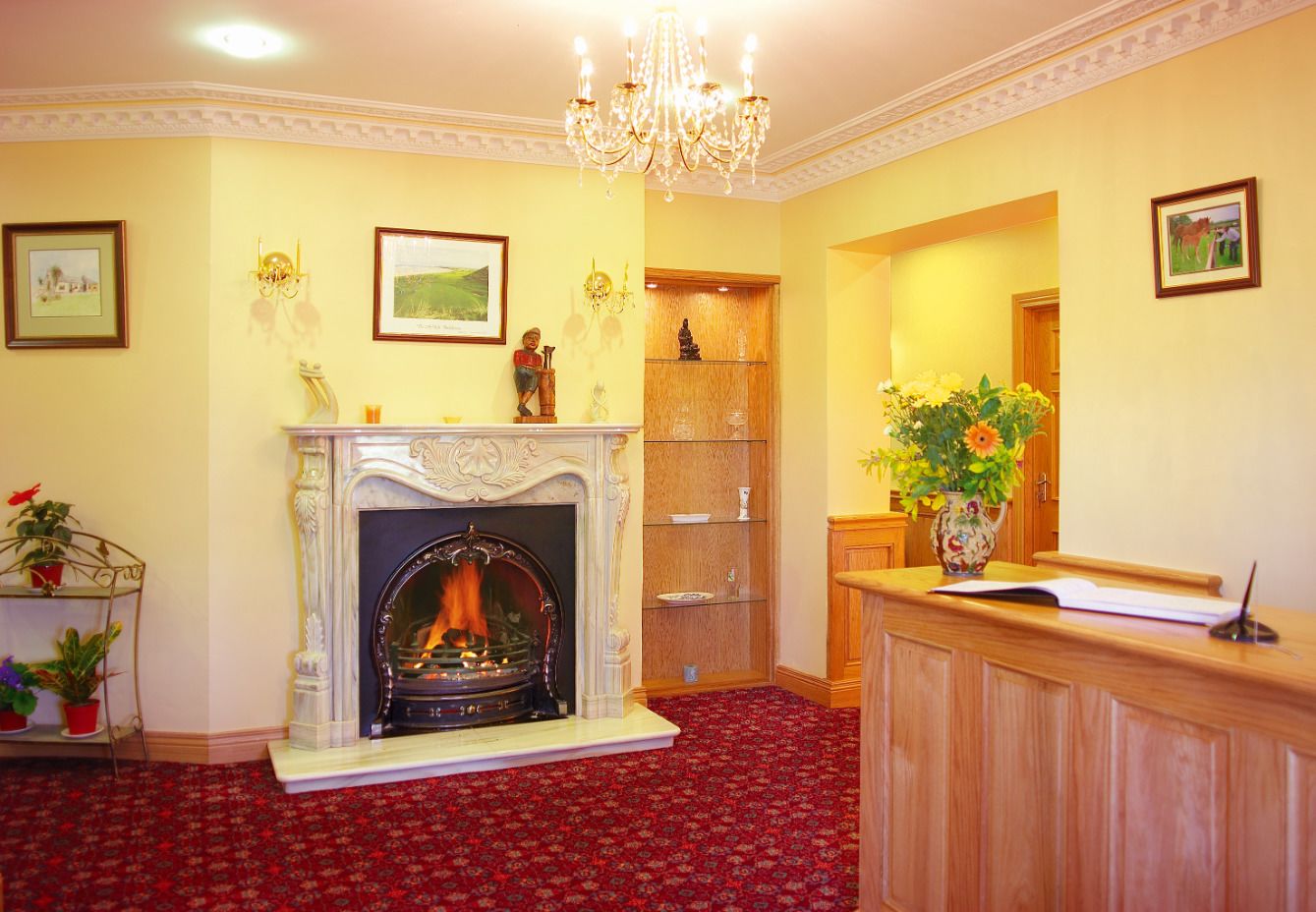 A room with a fireplace, a reception desk, and a red carpet.