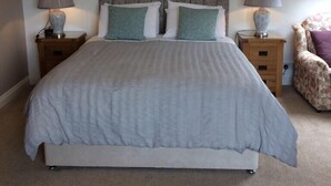 A bedroom with a bed, two nightstands, a chair, and a ceiling light fixture. - Cashen Course House (Ballybunion)