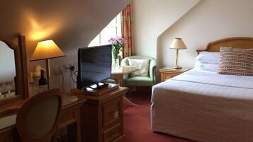 Ein Hotelzimmer mit Schreibtisch, Fernseher, Bett und Stuhl.